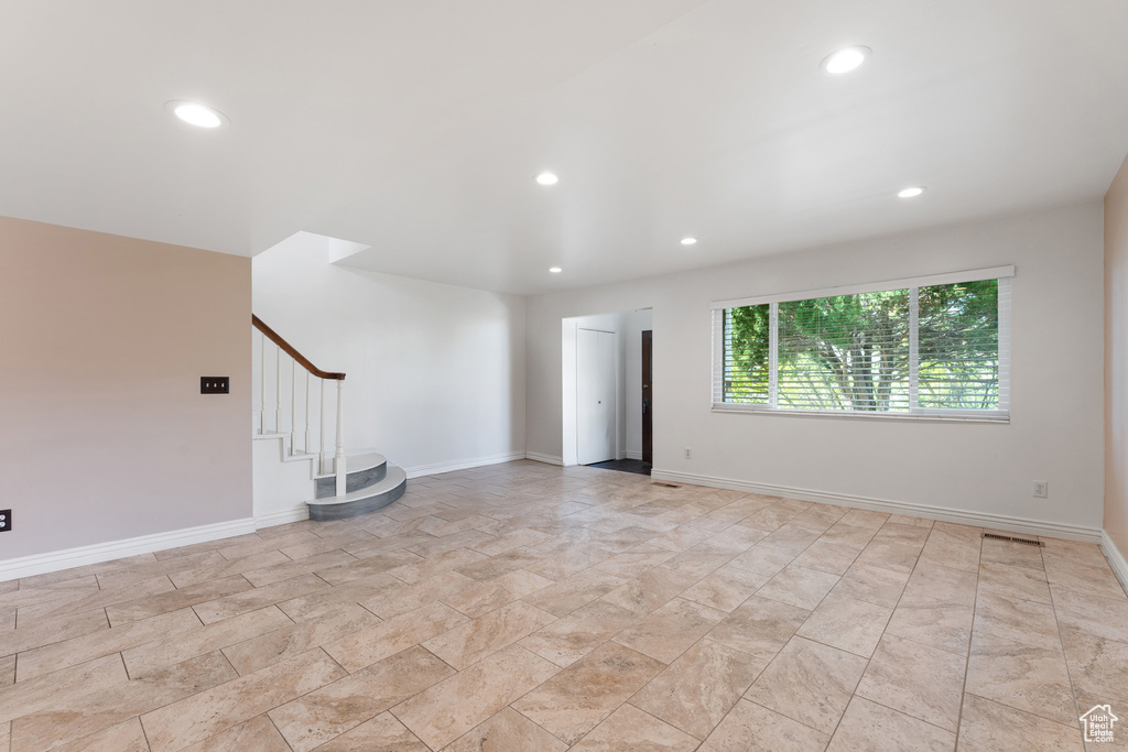 Unfurnished living room featuring stairway, baseboards, and recessed lighting