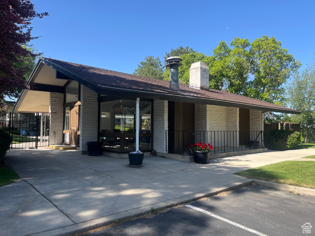 View of front of house featuring a chimney, brick siding, and covered porch