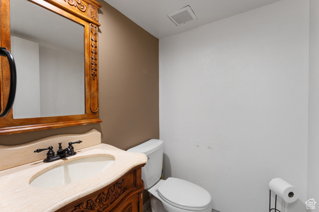 Bathroom featuring toilet, vanity, and visible vents