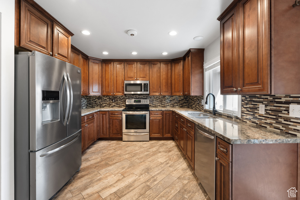 Kitchen with tasteful backsplash, stone countertops, stainless steel appliances, and a sink