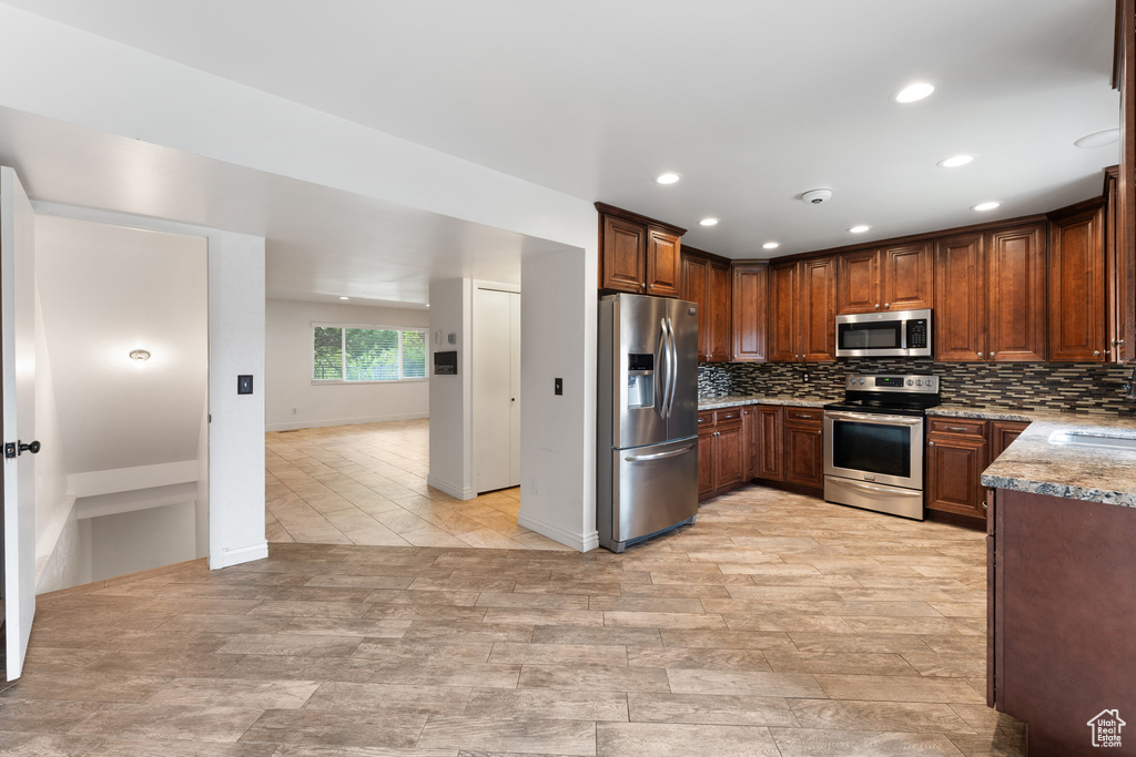 Kitchen featuring stainless steel appliances, a sink, tasteful backsplash, recessed lighting, and light stone counters