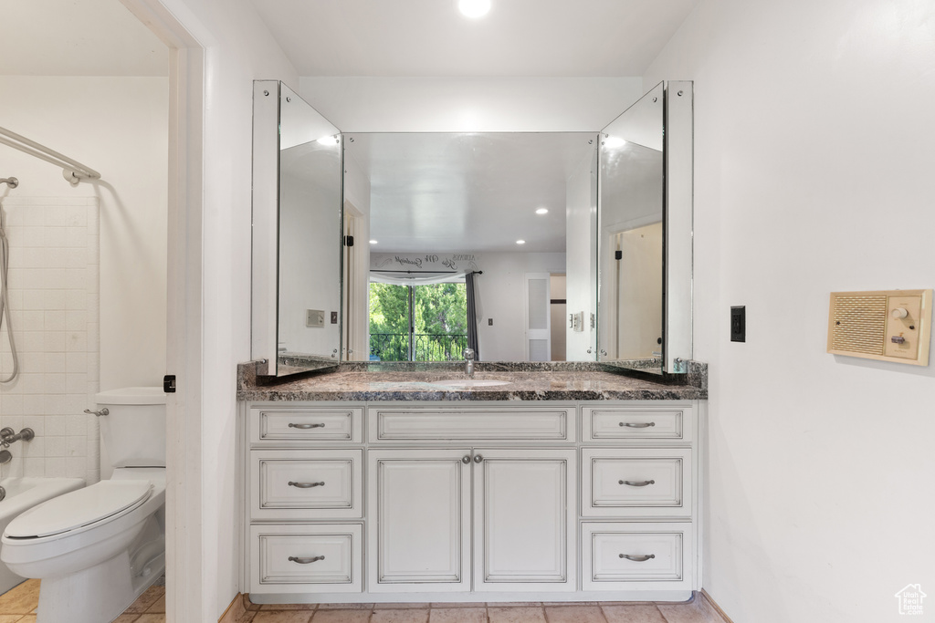 Bathroom with tile patterned flooring, washtub / shower combination, toilet, and vanity