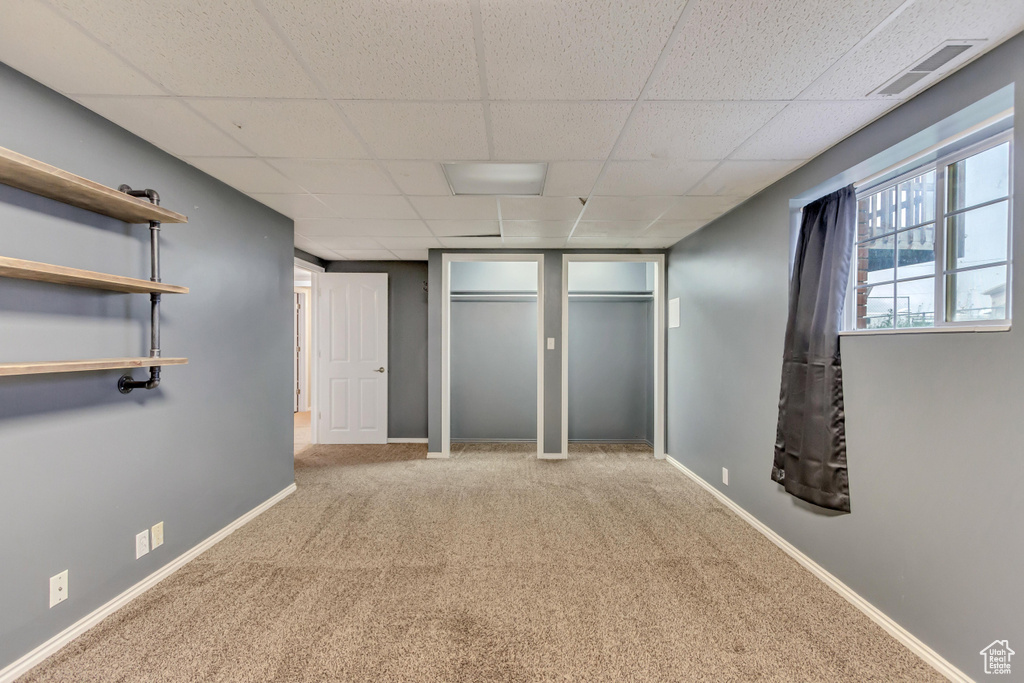 Unfurnished bedroom with baseboards, visible vents, a paneled ceiling, and carpet