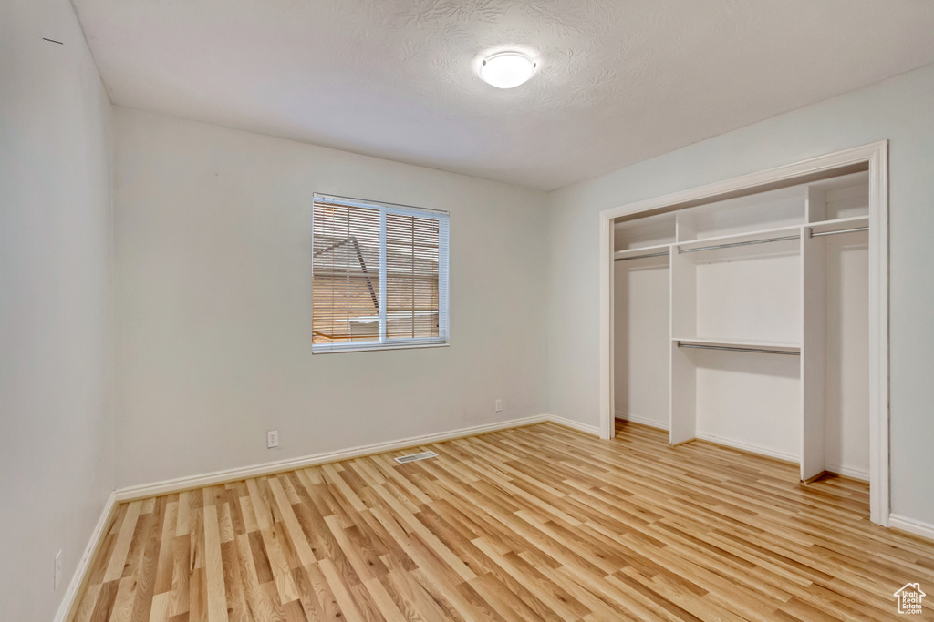 Unfurnished bedroom with light wood-style floors, a closet, baseboards, and visible vents