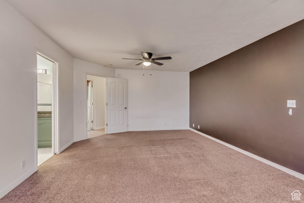 Spare room with a ceiling fan, baseboards, and light colored carpet