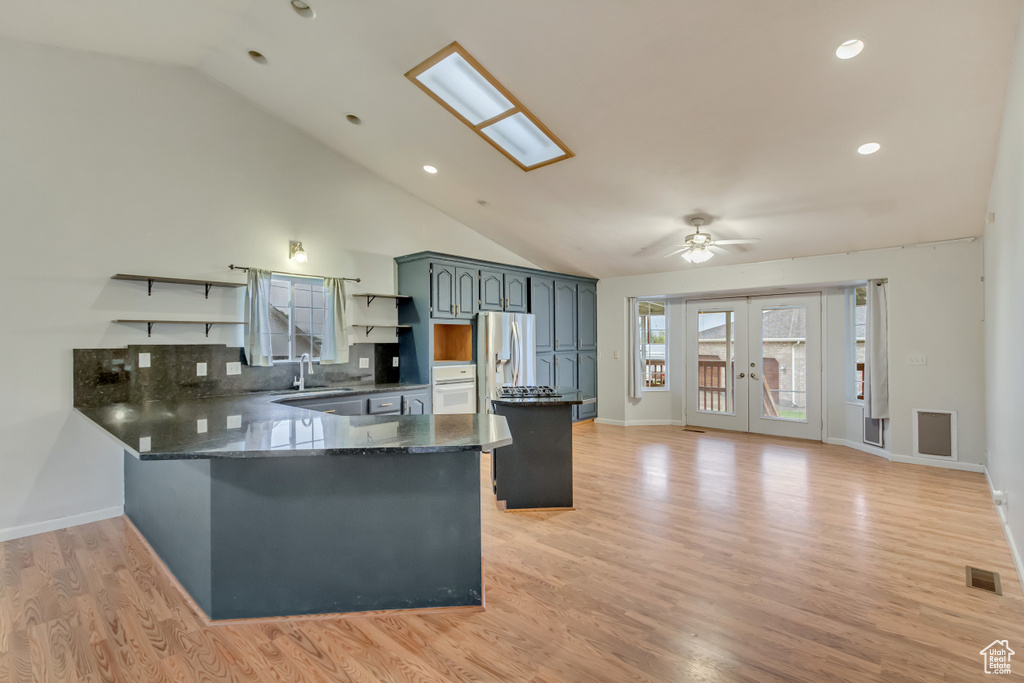 Kitchen with a peninsula, lofted ceiling, open shelves, and visible vents