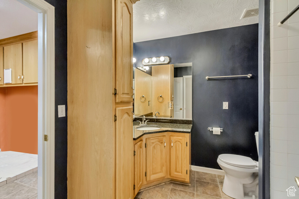 Bathroom with tile patterned floors, toilet, visible vents, baseboards, and vanity