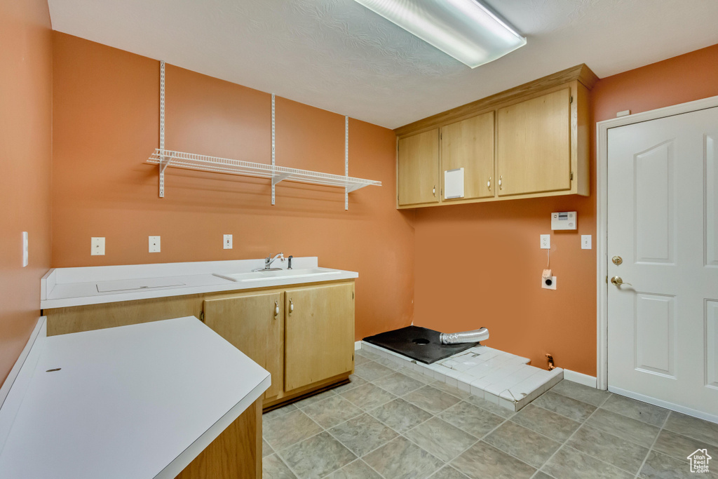 Laundry area with cabinet space, baseboards, electric dryer hookup, and a sink