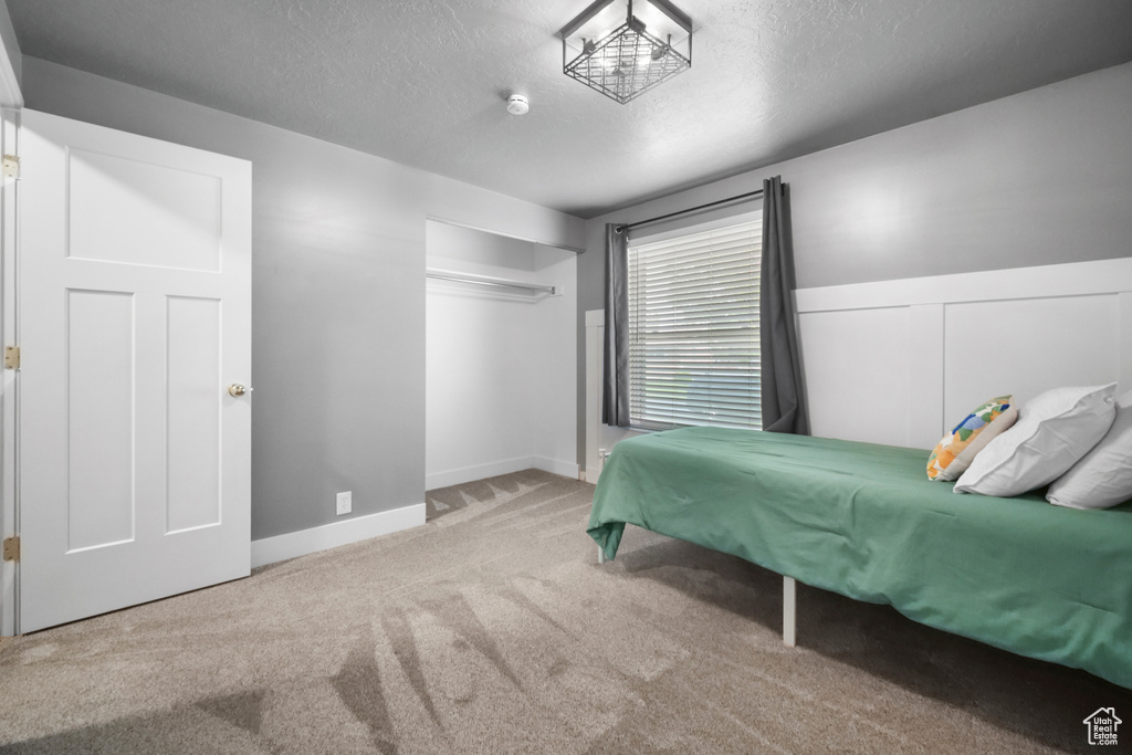 Bedroom with carpet floors, baseboards, and a textured ceiling
