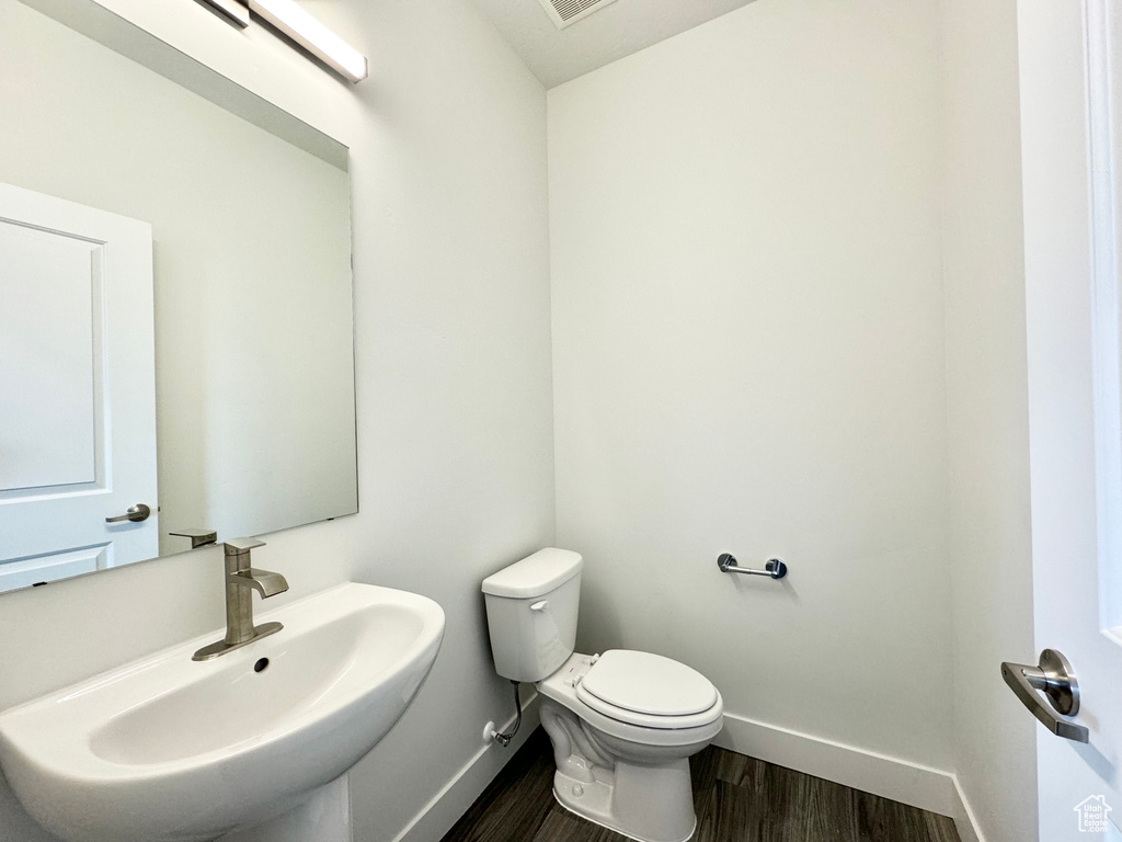 Bathroom with toilet, wood finished floors, a sink, and baseboards
