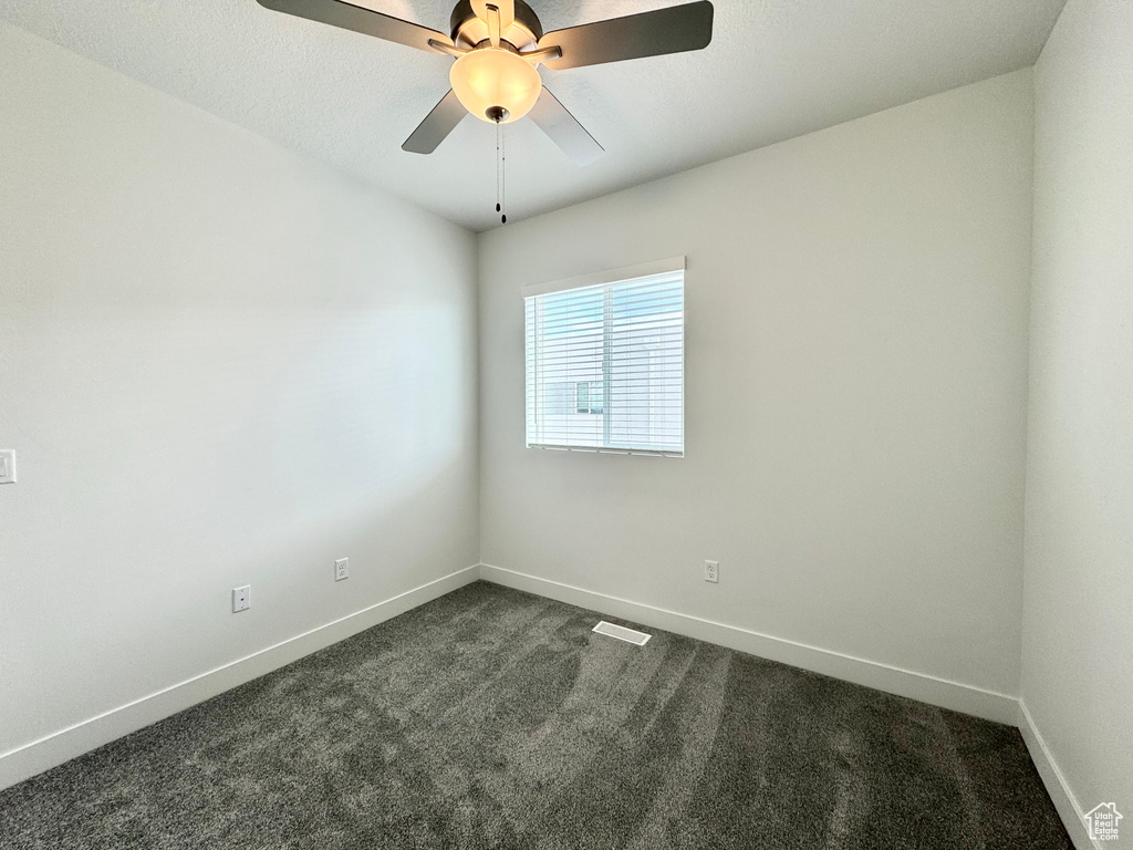 Spare room with baseboards, dark colored carpet, and visible vents
