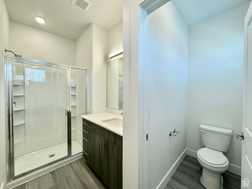 Full bath with a shower stall, wood finished floors, and visible vents