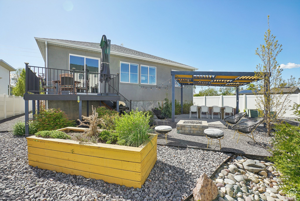 Back of property with stucco siding, a deck, a fenced backyard, a patio area, and a fire pit