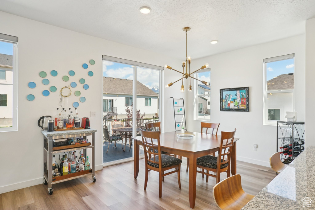 Dining room featuring baseboards, light wood-style flooring, and a notable chandelier