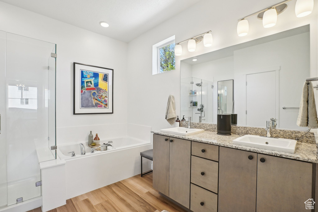Full bath with a garden tub, a sink, wood finished floors, and a shower stall