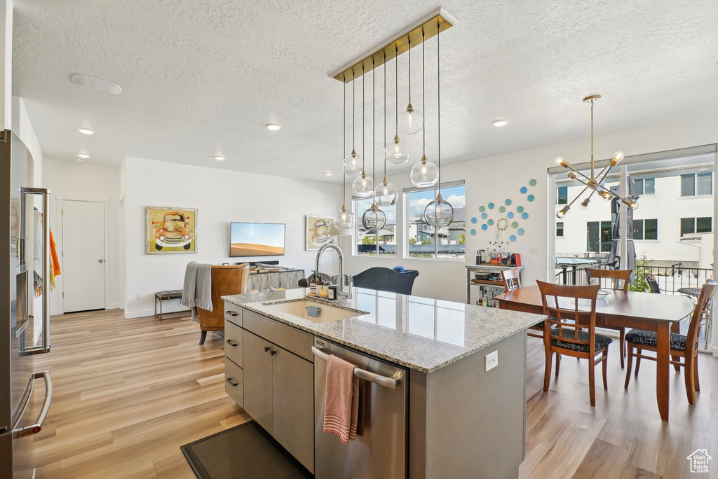 Kitchen with a sink, light wood-style floors, a textured ceiling, and dishwasher