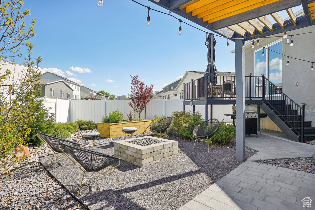 View of patio with a deck, fence, a fire pit, and stairs