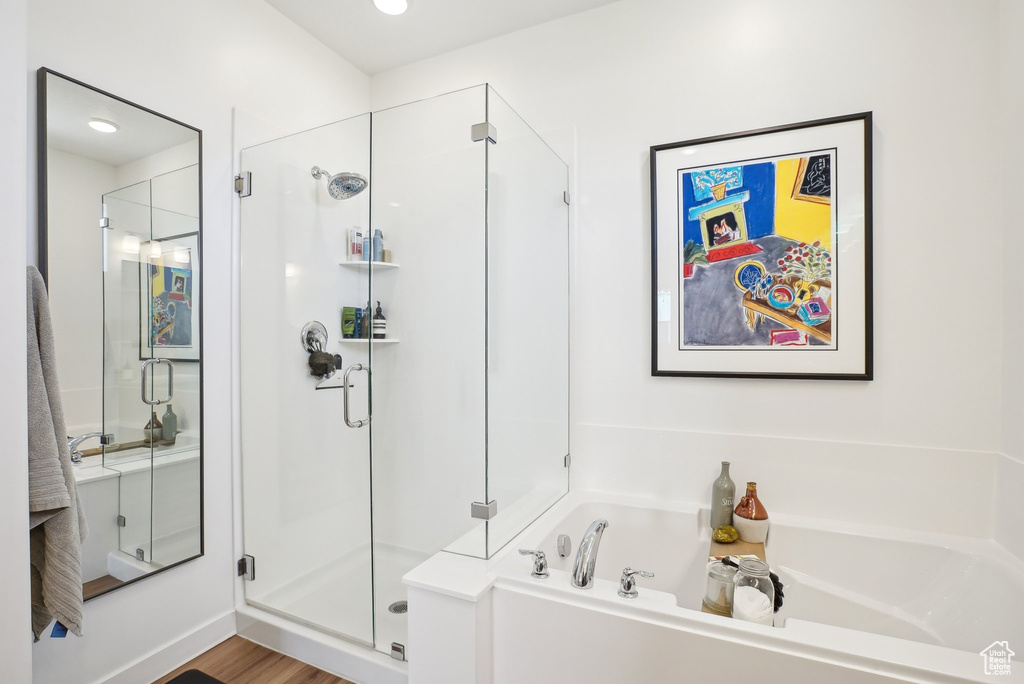 Bathroom with a garden tub, wood finished floors, and a shower stall