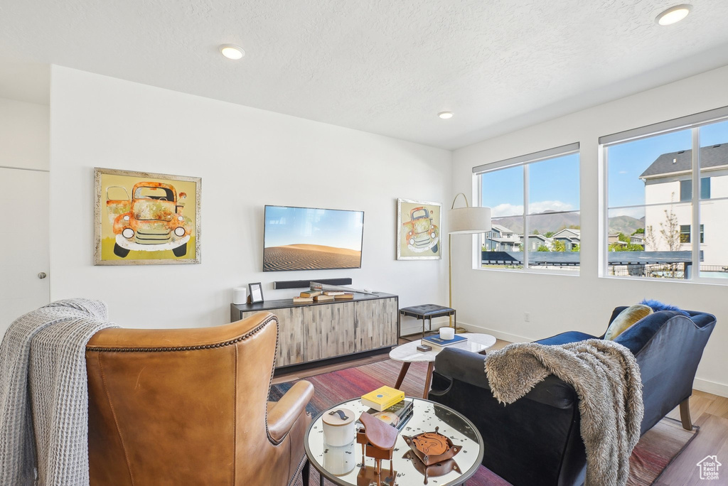 Living area with baseboards, recessed lighting, a textured ceiling, and wood finished floors