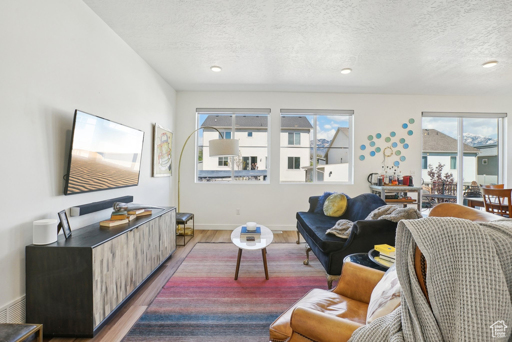 Living room featuring recessed lighting, baseboards, light wood finished floors, and a textured ceiling
