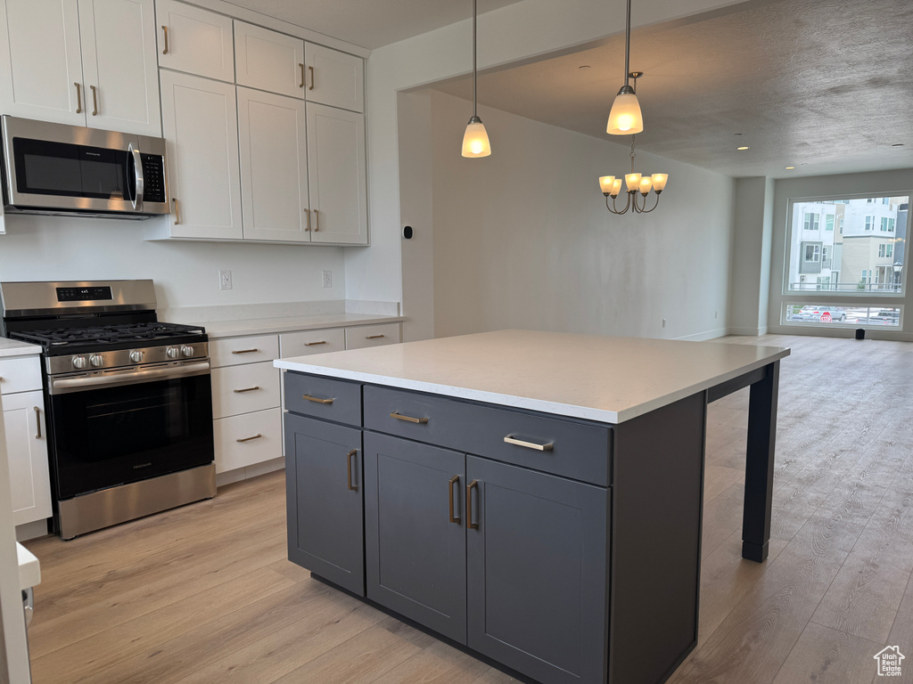 Kitchen featuring light wood-type flooring, open floor plan, light countertops, and appliances with stainless steel finishes