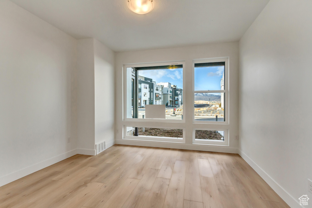 Spare room featuring light wood finished floors, baseboards, and visible vents