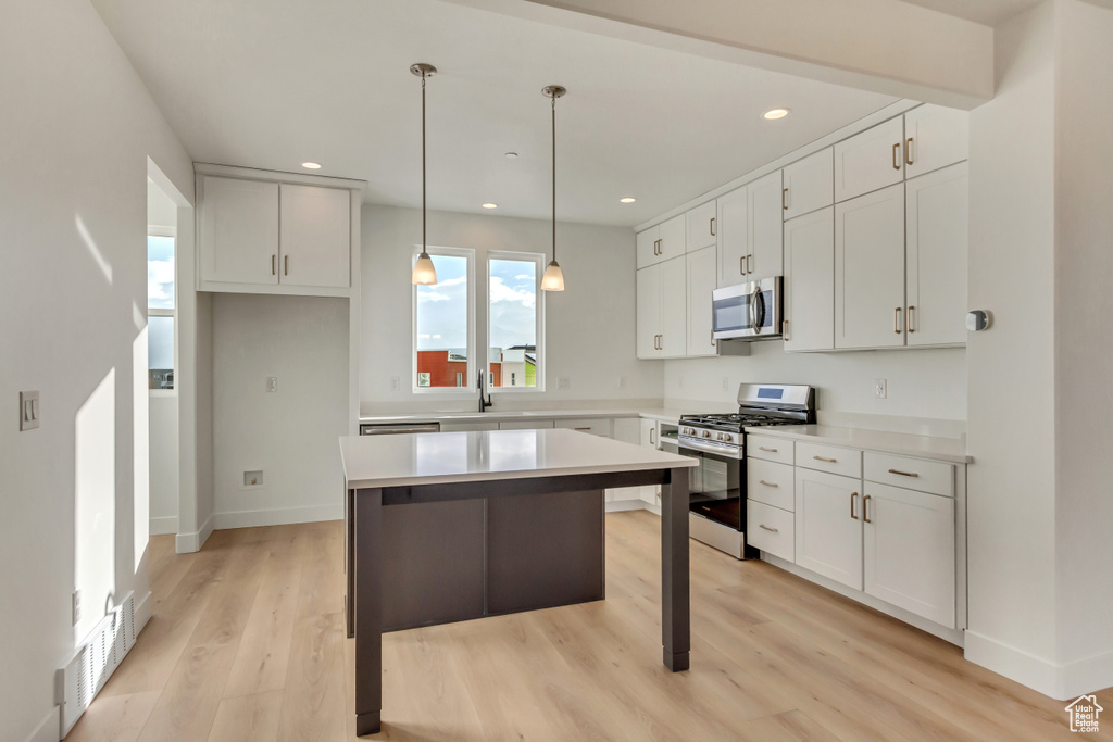 Kitchen featuring recessed lighting, light wood-type flooring, a kitchen island, appliances with stainless steel finishes, and white cabinetry