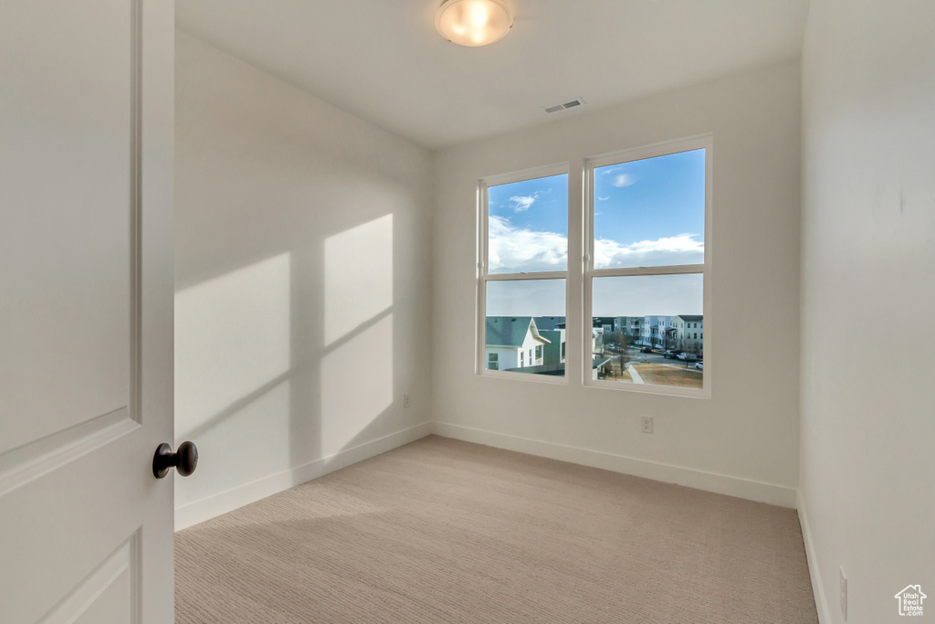 Spare room with light colored carpet, baseboards, and visible vents