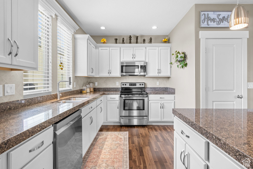 Kitchen with white cabinetry, appliances with stainless steel finishes, a sink, and dark wood-type flooring