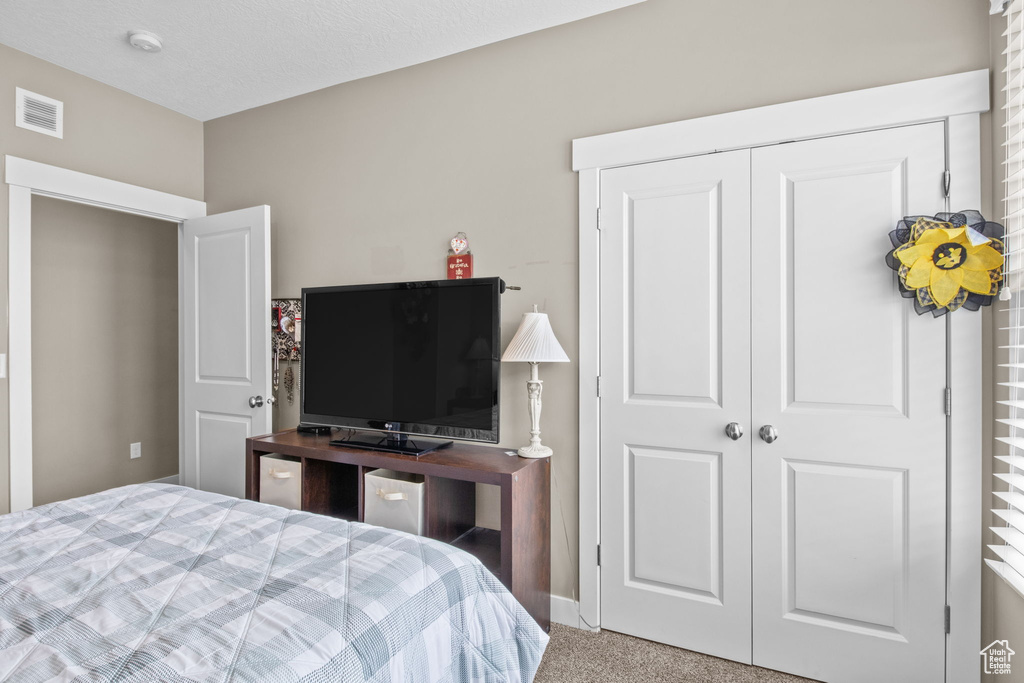 Bedroom featuring visible vents, carpet, and a closet