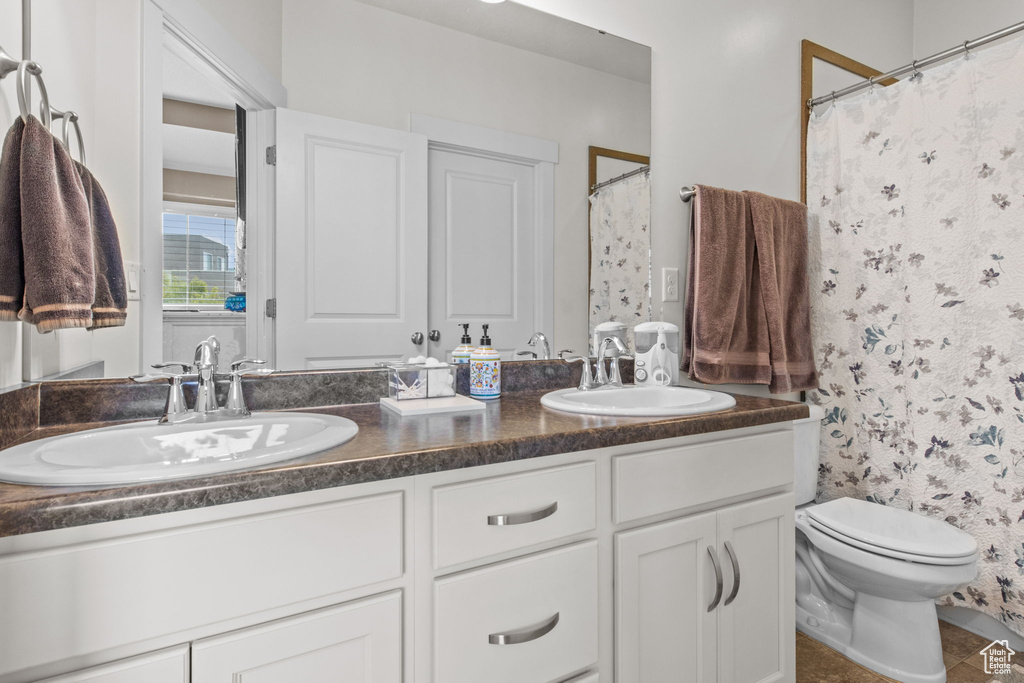 Full bath featuring a shower with shower curtain, double vanity, toilet, and a sink