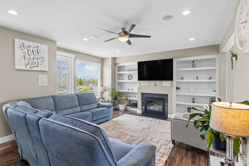 Living room with a textured ceiling, dark wood-style floors, and ceiling fan