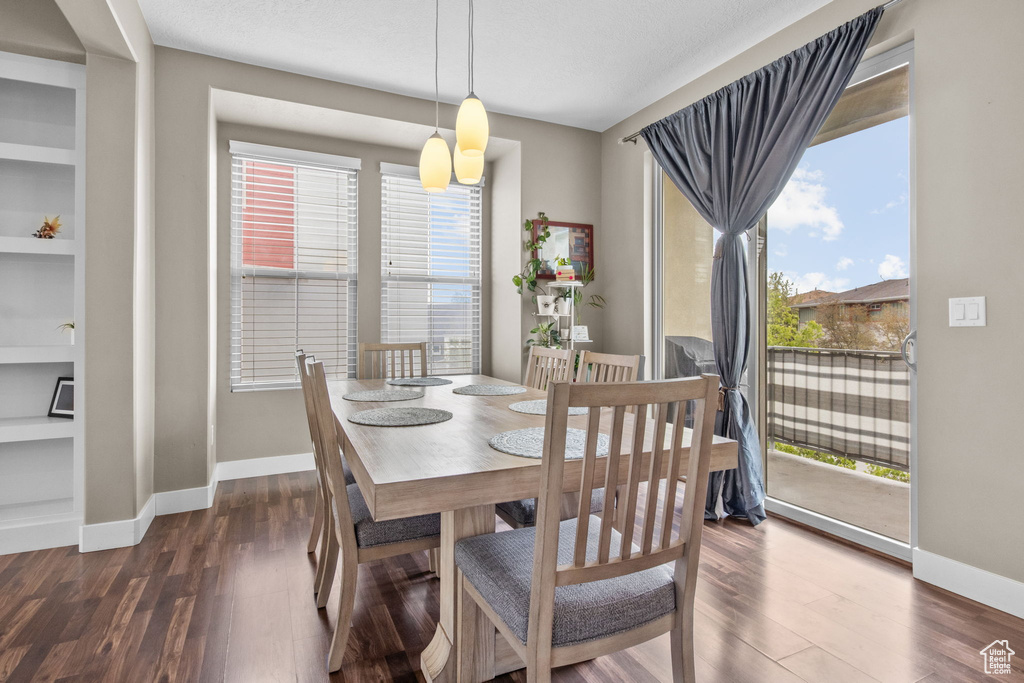 Dining room featuring baseboards, built in shelves, and dark wood-style flooring