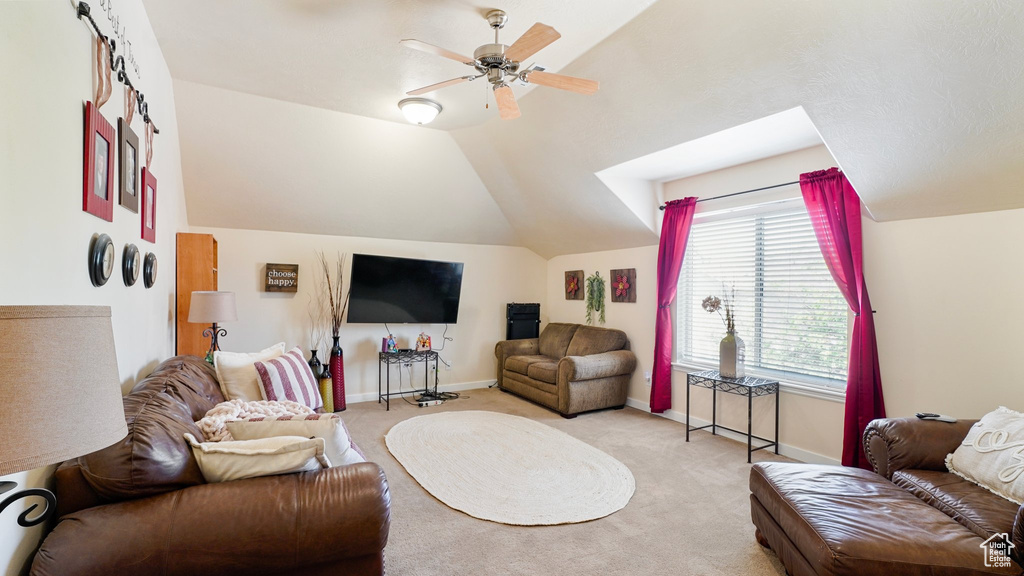 Living room featuring light colored carpet, lofted ceiling, a ceiling fan, and baseboards