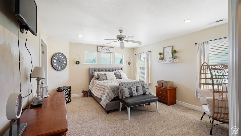 Bedroom featuring visible vents, light carpet, a ceiling fan, and baseboards