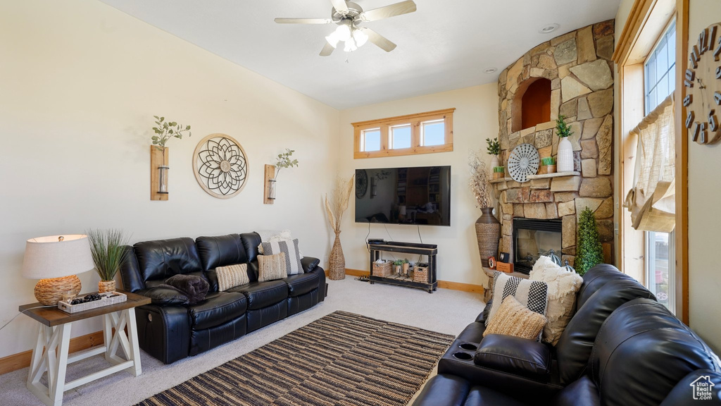 Living room with a fireplace, carpet flooring, baseboards, and a ceiling fan