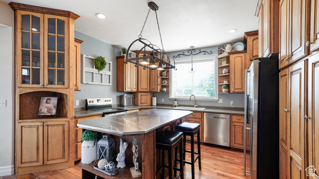 Kitchen featuring stainless steel appliances, stainless steel counters, a sink, open shelves, and a breakfast bar