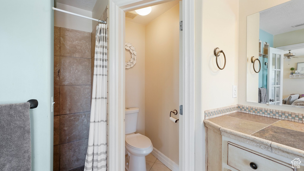 Bathroom with tile patterned floors, vanity, toilet, visible vents, and tiled shower