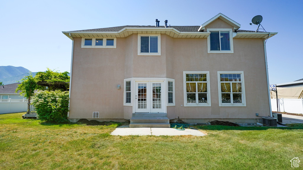 Rear view of house featuring stucco siding, fence, a yard, and french doors