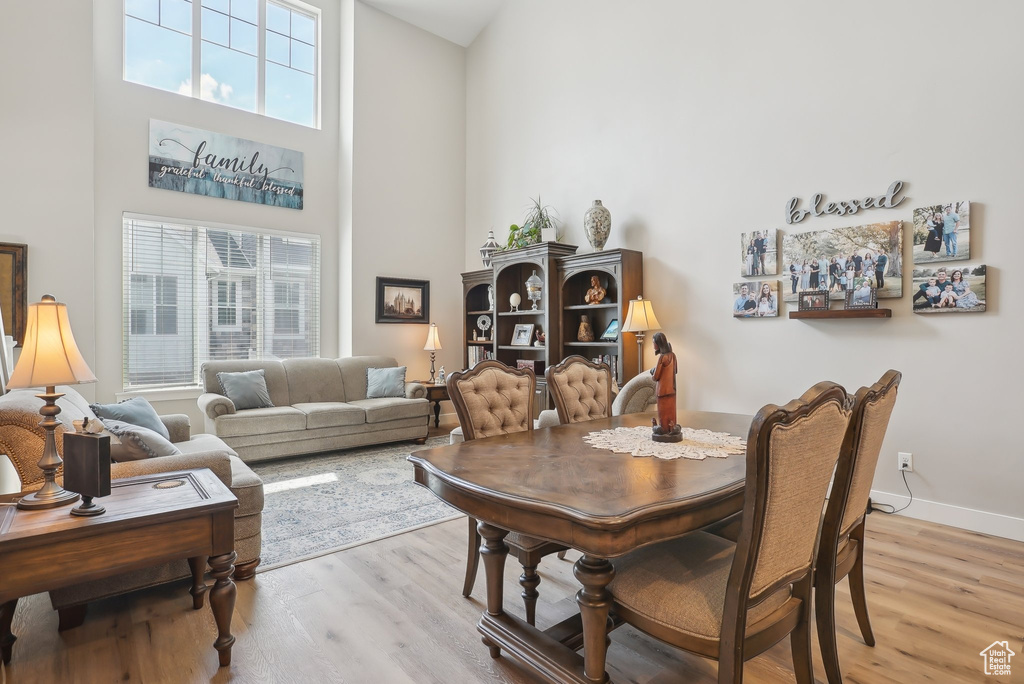 Dining room with a towering ceiling, baseboards, and light wood-style floors