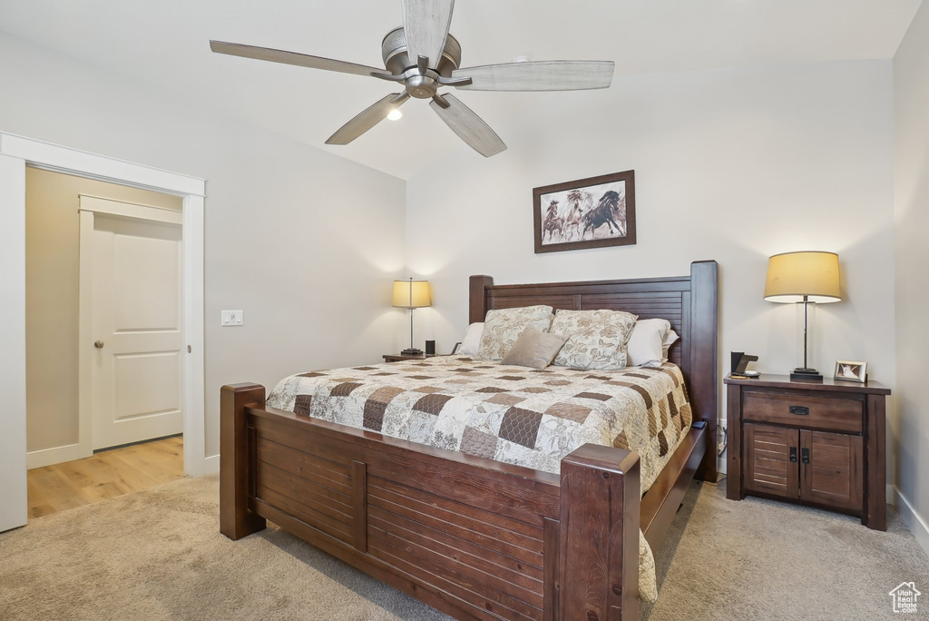 Bedroom with lofted ceiling, a ceiling fan, light colored carpet, and baseboards
