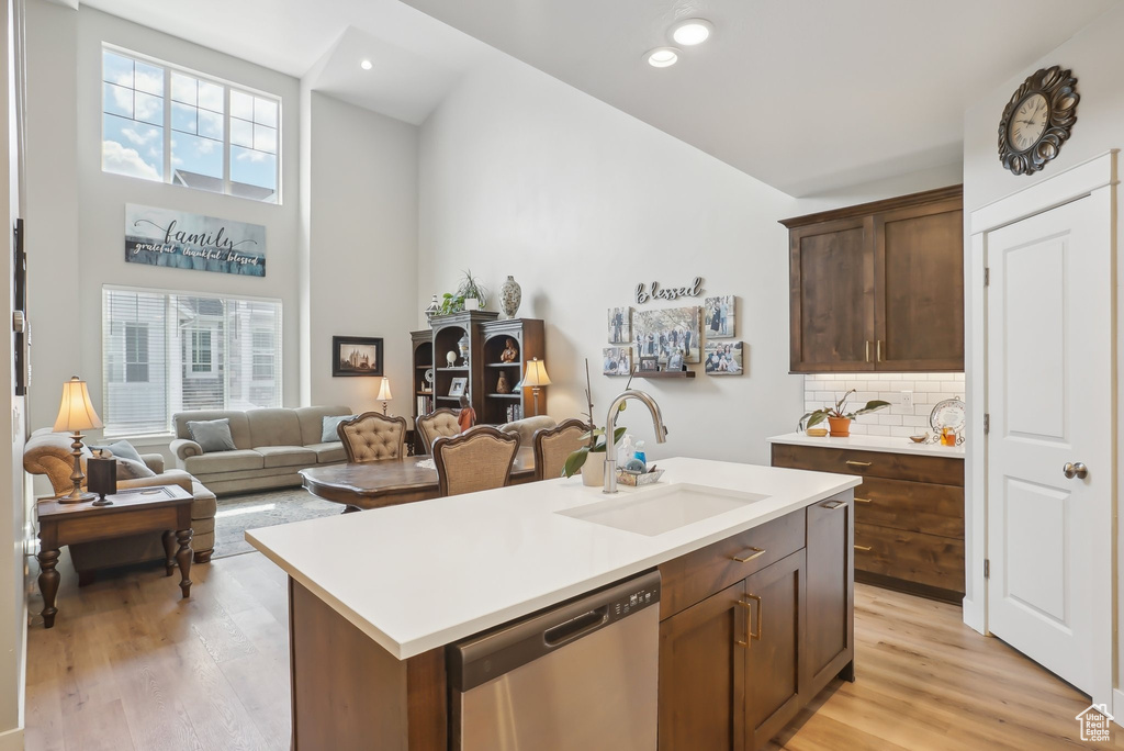 Kitchen featuring decorative backsplash, dishwasher, light wood finished floors, and a sink