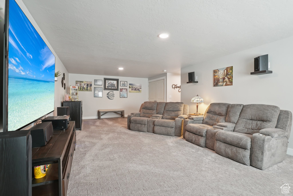 Carpeted living room featuring a textured ceiling, recessed lighting, and baseboards