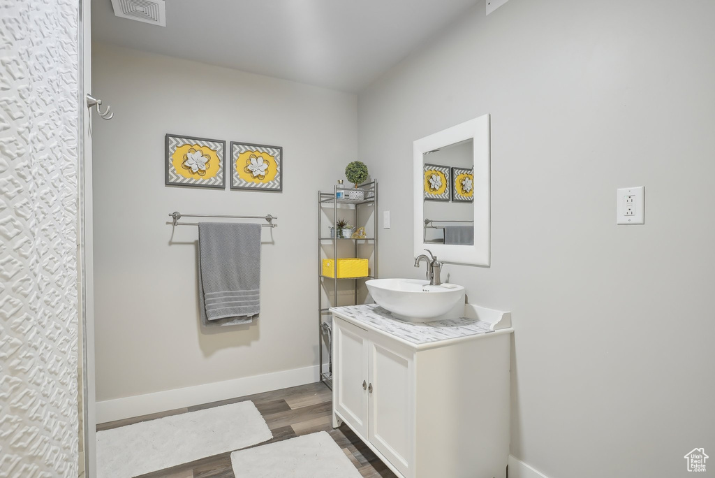 Full bathroom with baseboards, visible vents, wood finished floors, and vanity