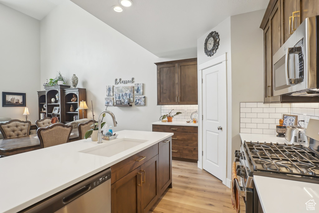 Kitchen with light wood finished floors, a sink, stainless steel appliances, and light countertops