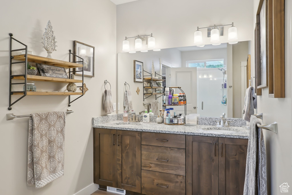 Full bath with double vanity, visible vents, and a sink