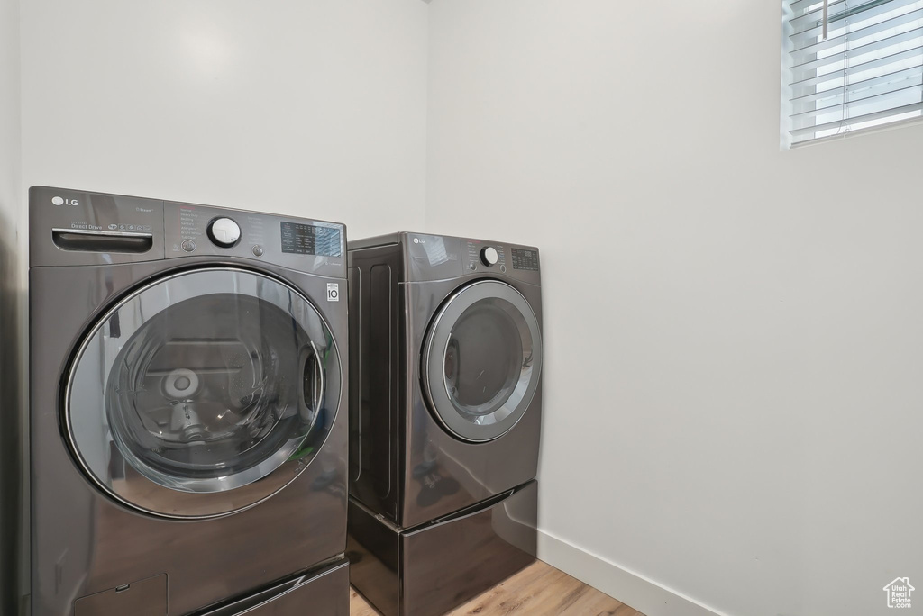 Laundry area with washer and dryer, light wood-style flooring, laundry area, and baseboards