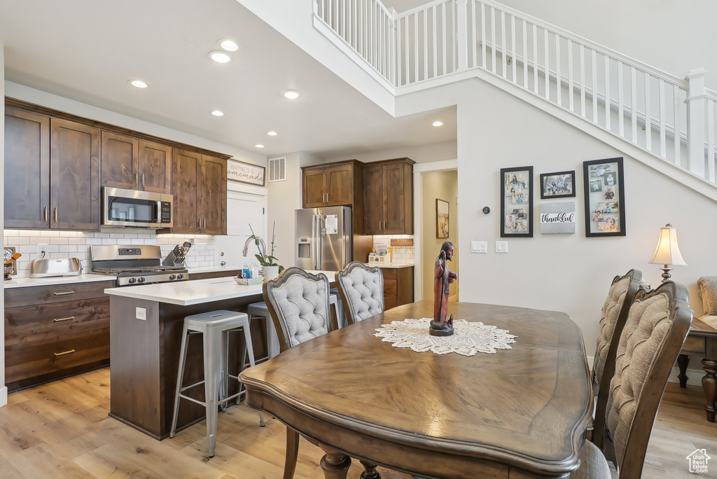 Dining area featuring recessed lighting, visible vents, a towering ceiling, and light wood-type flooring