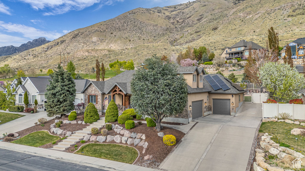View of front facade featuring fence, a residential view, solar panels, stucco siding, and driveway