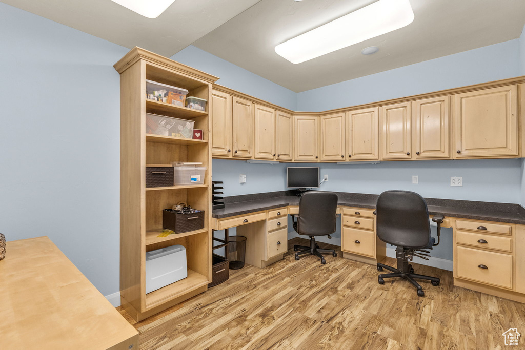 Office with built in study area and light wood-style flooring